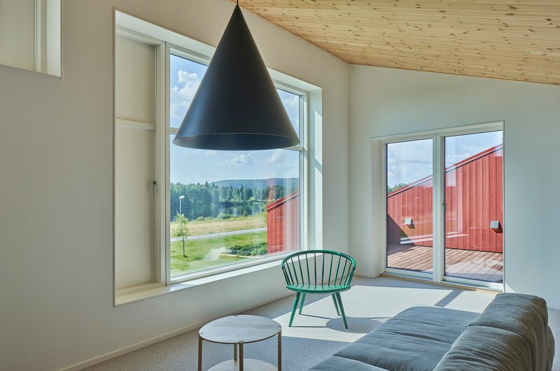 Living room with plywood ceiling and deep window reveals framing views of a red courtyard structure and landscape