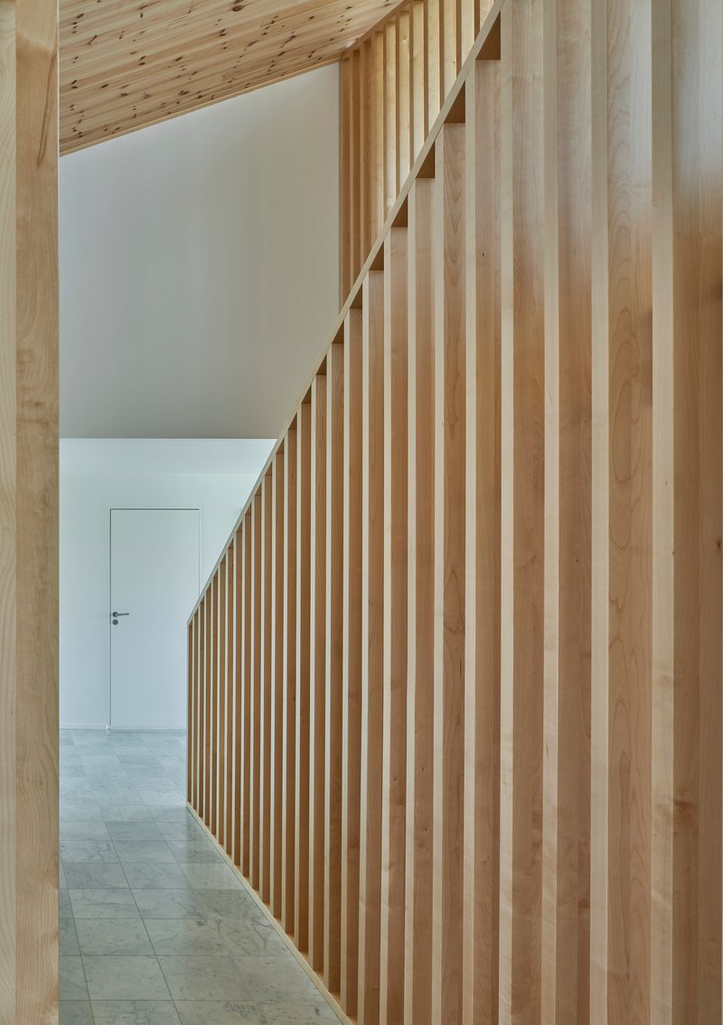 Hallway with vertical timber slat wall leading to a white door and exposed ceiling