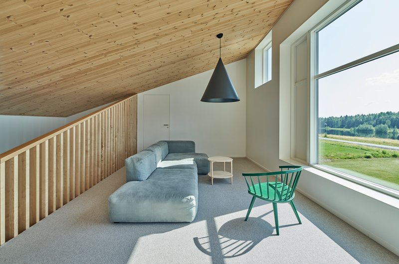 Upper level seating area with slatted wood railing and sloped timber ceiling under daylight