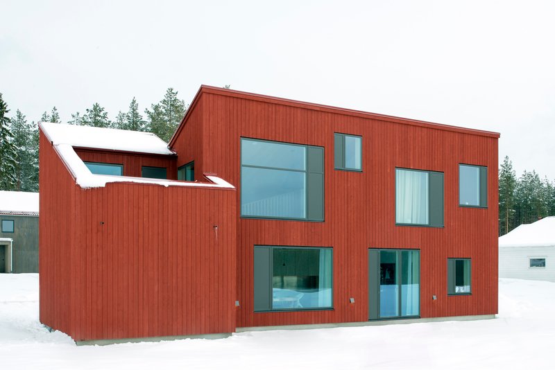 Garden facade of the red clad volumes with snow on the ground in winter