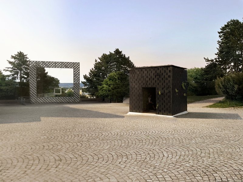 Two basketweave brick pavilions on a cobblestone plaza at dusk with trees in the background