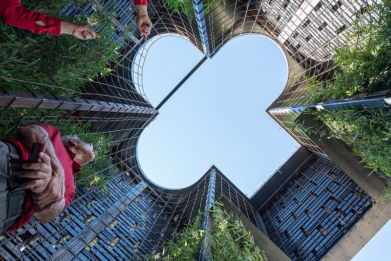 Upward view through the clover-shaped opening framed by planted vertical screens and visitors