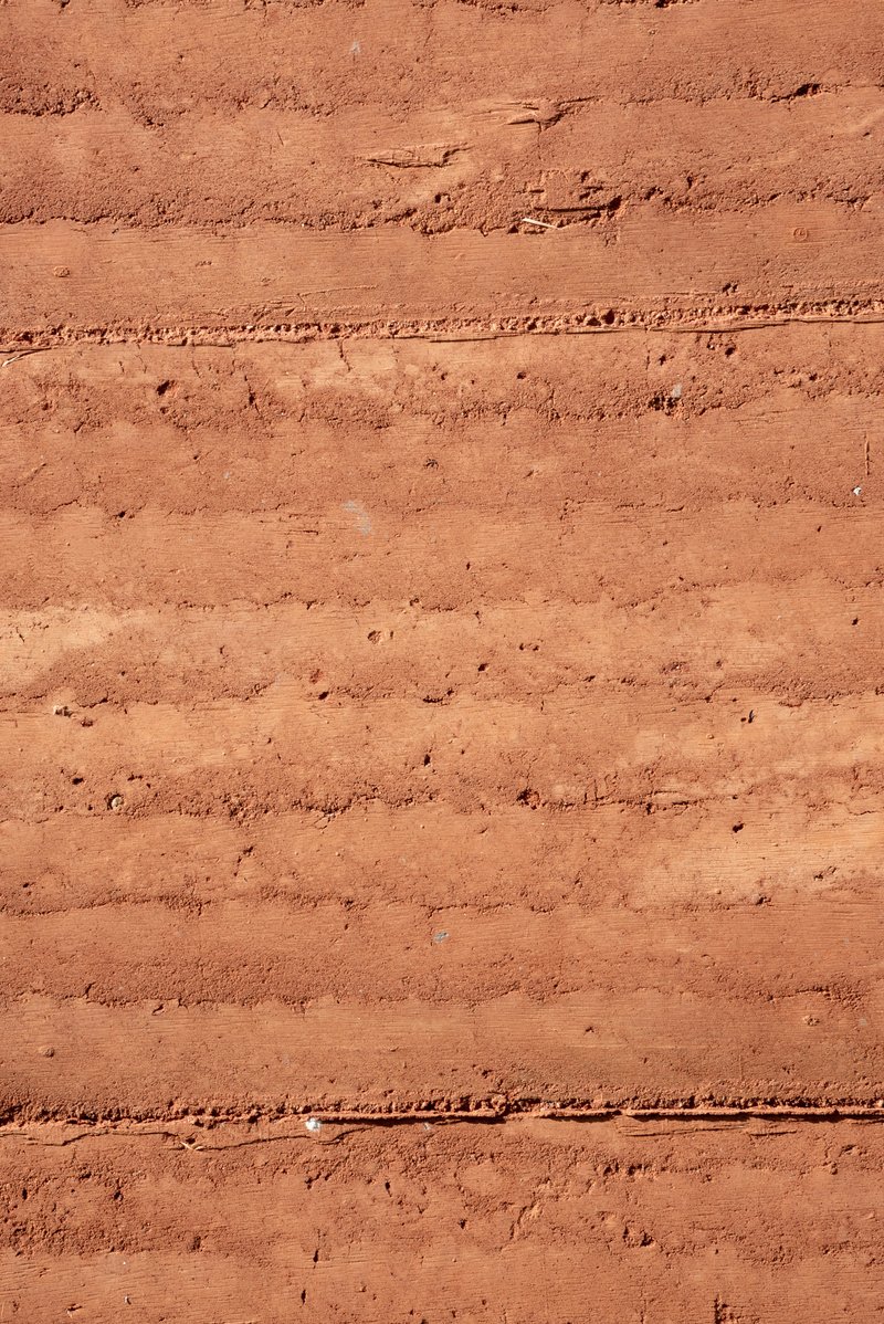 Close-up of layered rammed earth wall surface showing horizontal stratification and natural texture