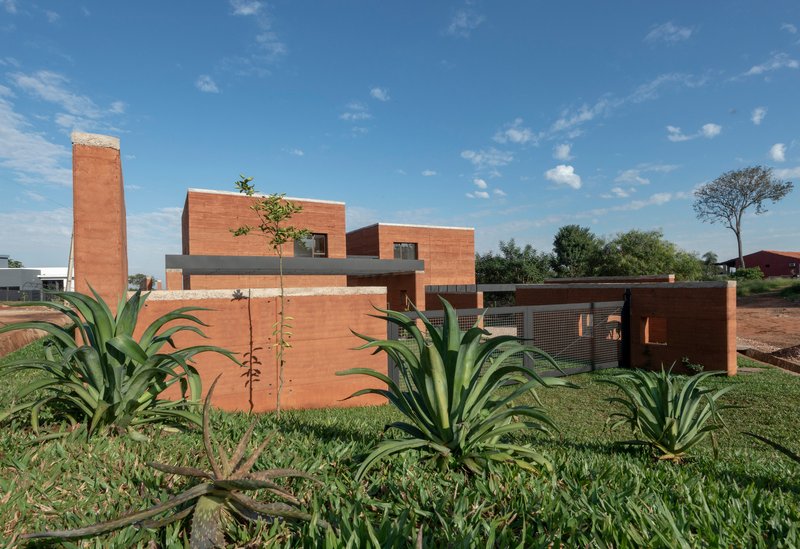 Side elevation showing rammed earth volumes and a planted bed of agave in the foreground