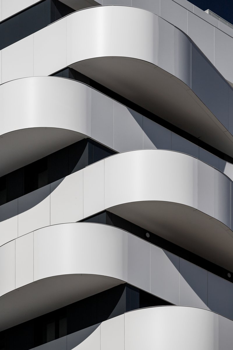 Close-up of the white curved balcony edges and recessed panels in afternoon shadow