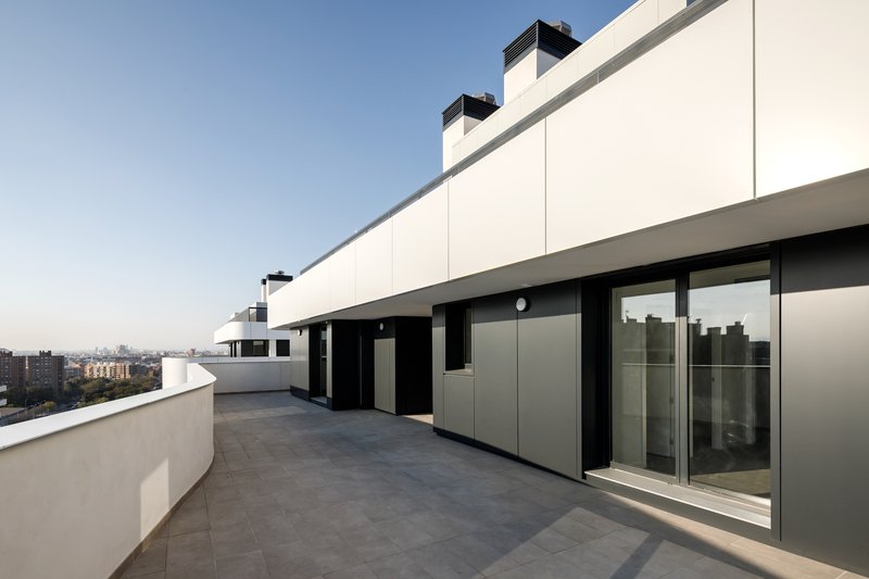 Rooftop terrace with grey tile paving and sliding glass doors at dusk