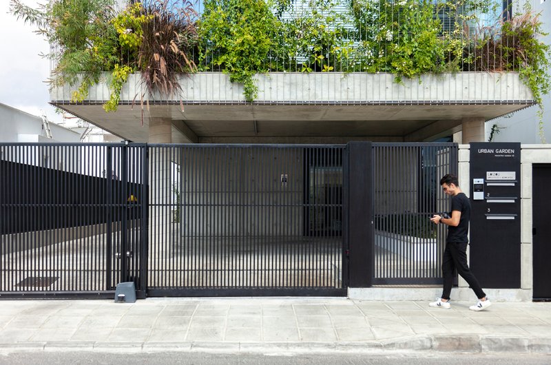 Ground-level entrance with corrugated metal gate and a person walking past on the sidewalk