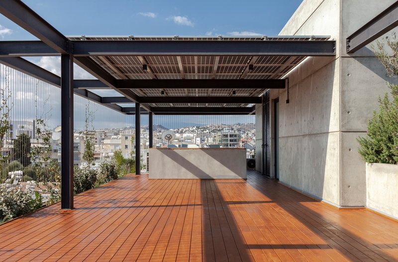Rooftop terrace with solar panel canopy on steel beams above timber decking and concrete walls