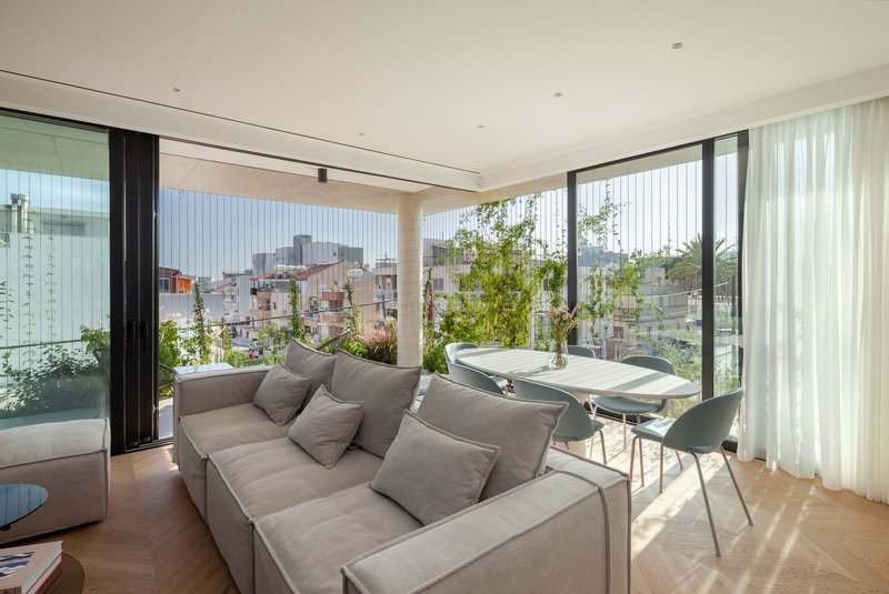 Living room opening onto terrace with vertical green screen and views across the low-rise neighborhood