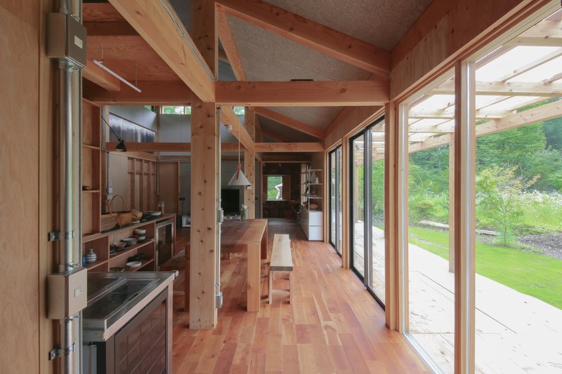 Living and dining space with exposed post-and-beam structure and full-height glass doors opening to garden