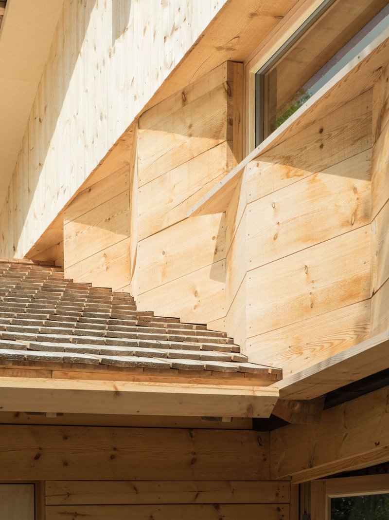 Exterior detail of cantilevered timber louvers extending over exposed beam structure and glass aperture