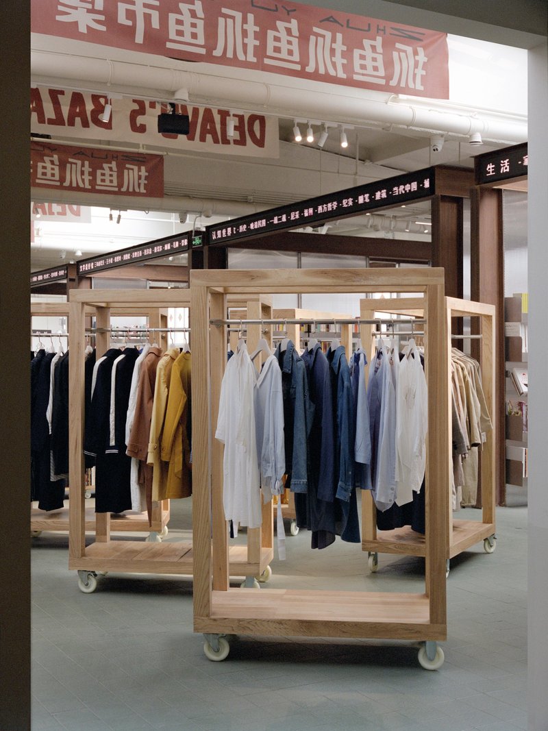 Freestanding timber clothing rack on casters beneath red signage and exposed ductwork