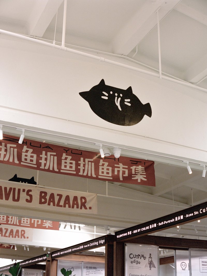 Black cat silhouette sign mounted on white wall above retail graphics and track lighting