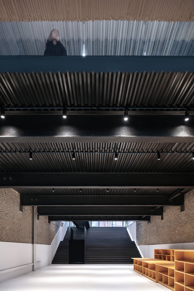 Upward view of stacked floor levels with vertical slat screens and a visitor standing on the translucent balcony