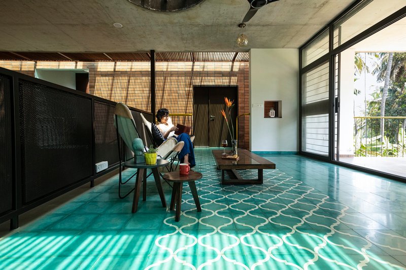 Upper floor sitting area with patterned turquoise tiles and a person reading by the window