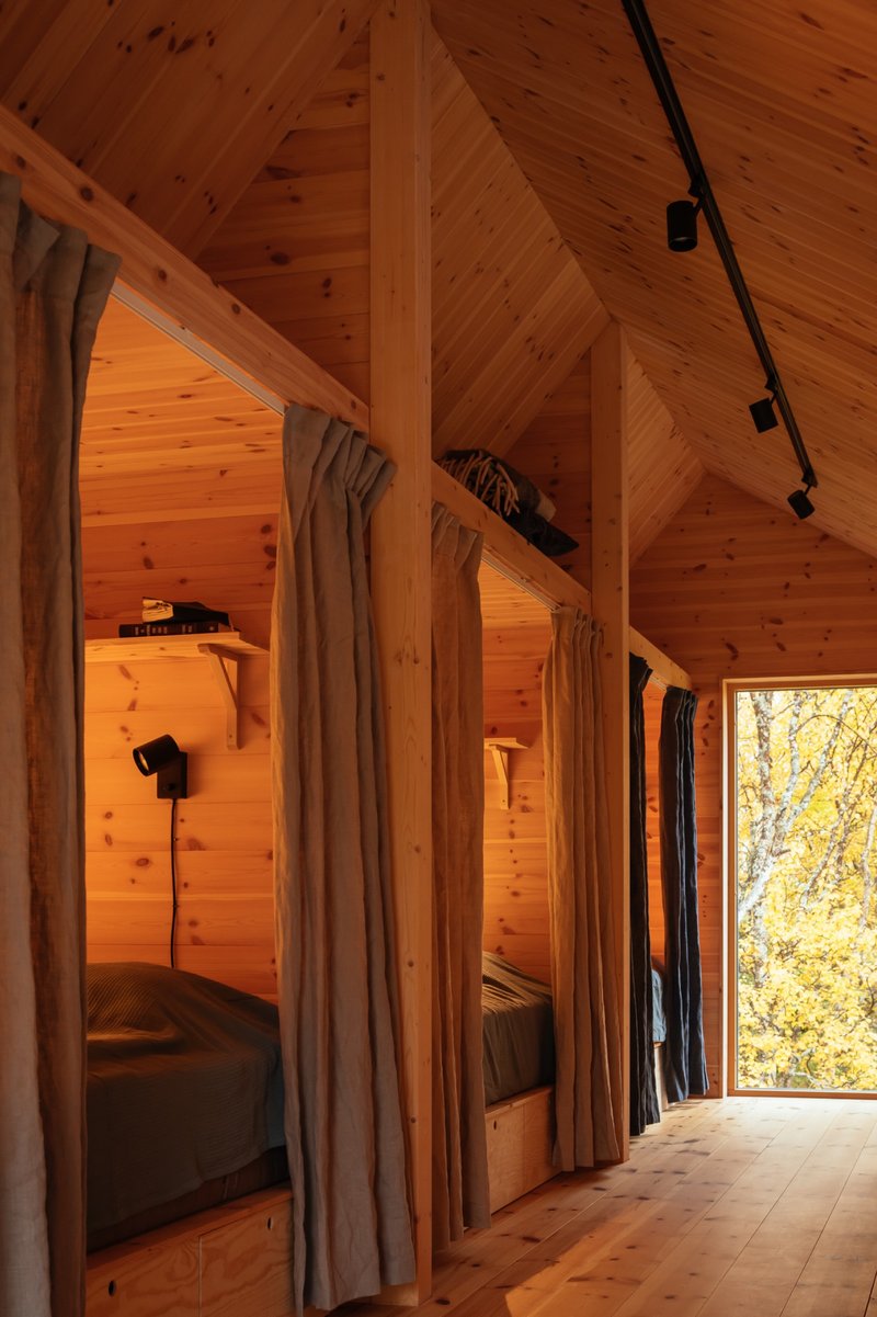 Sleeping alcoves with linen curtains along a timber-lined corridor under a vaulted ceiling