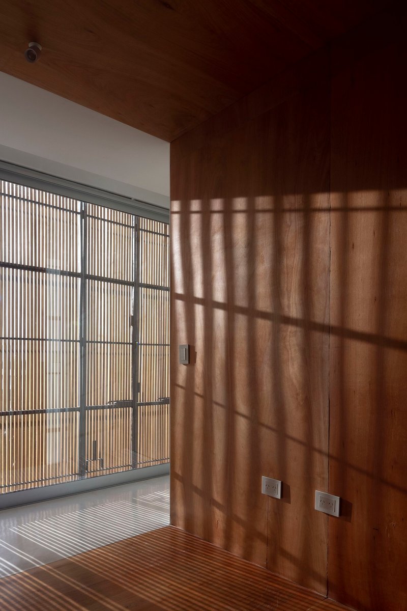 Timber-lined room with slatted screen casting shadow patterns across wall and floor