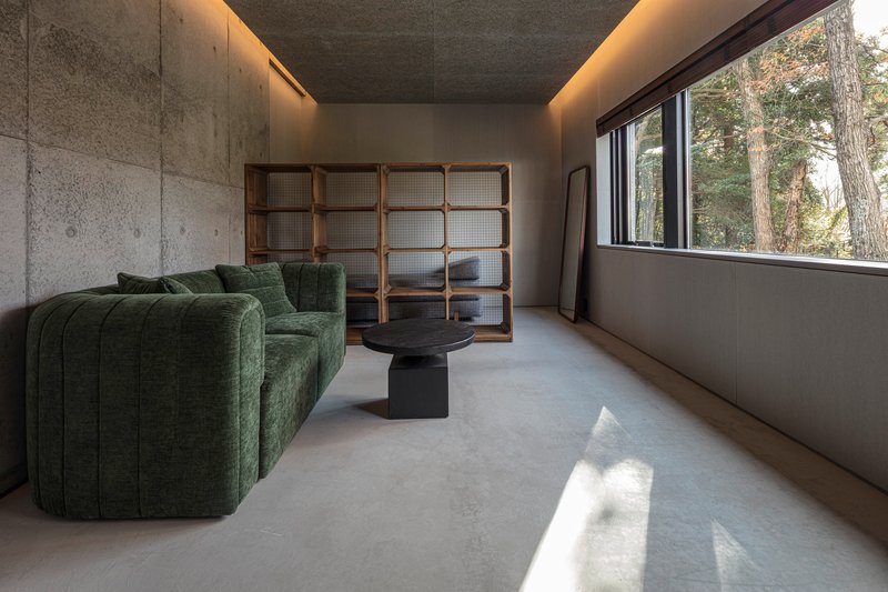 Interior room with concrete walls, cove lighting, and a gridded wood screen beside a window