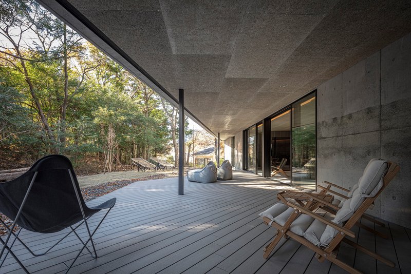 Covered timber deck terrace with folding canvas chairs overlooking wooded hillside in afternoon light