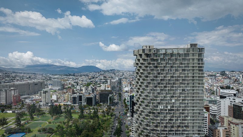 Aerial view of the staggered balcony tower against distant mountains and urban fabric below