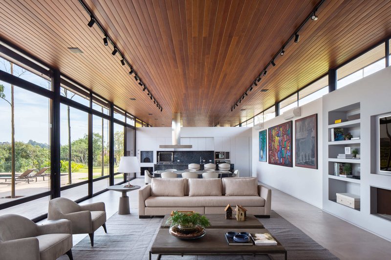 Open living space with wood slat ceiling and floor-to-ceiling glazing overlooking the lawn