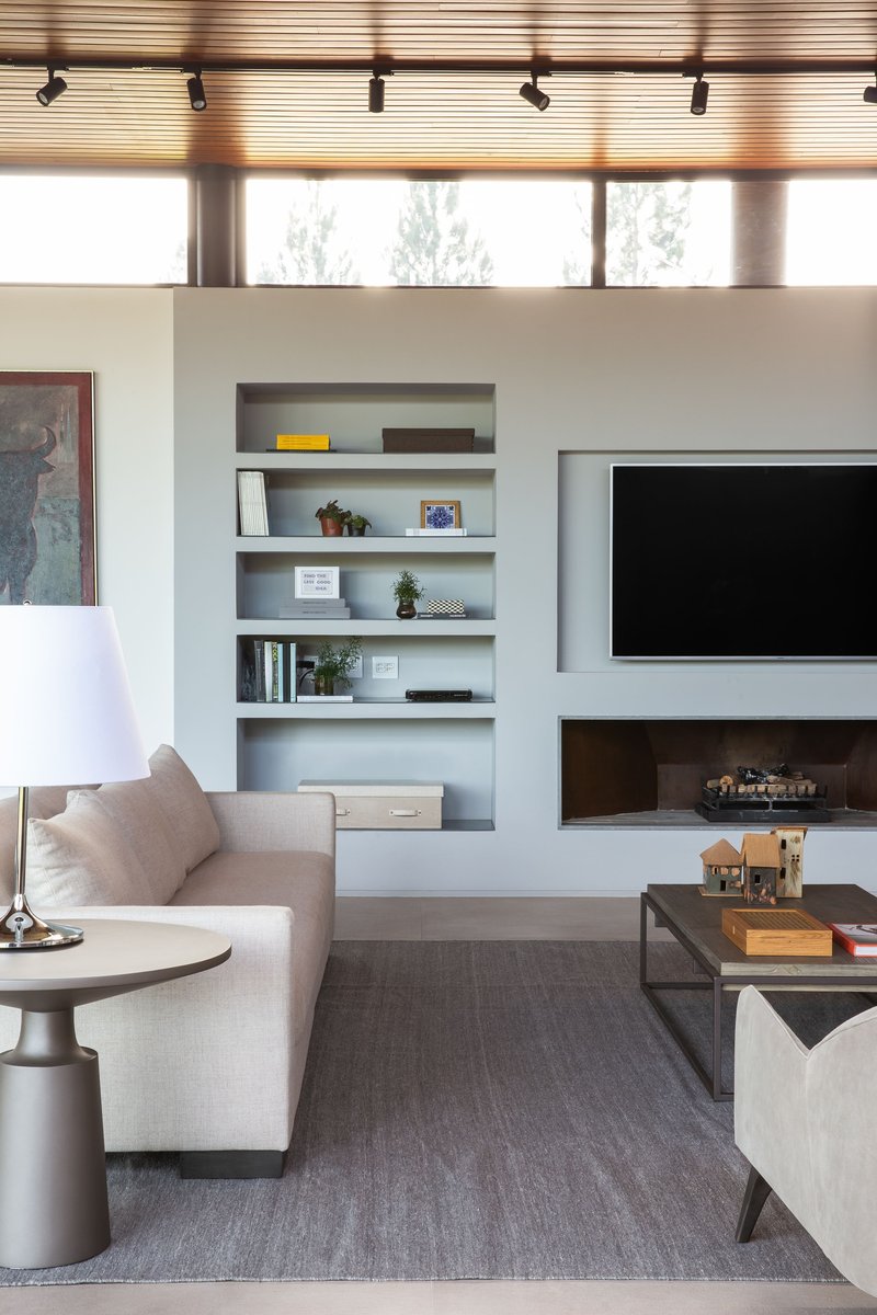 Living room with white built-in shelving and a horizontal fireplace below a mounted television