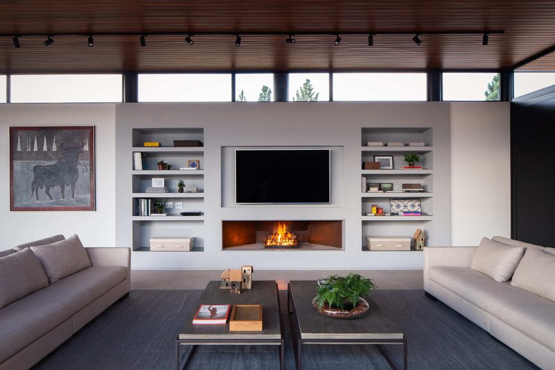Living room with white built-in shelving and recessed fireplace beneath a clerestory window band