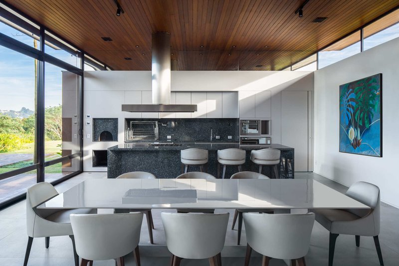Kitchen and dining area with black terrazzo island beneath a slatted timber ceiling