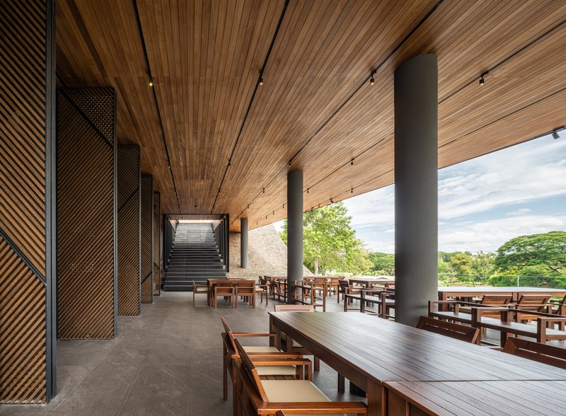 Interior corridor with perforated metal screens and timber ceiling leading to a staircase at the end