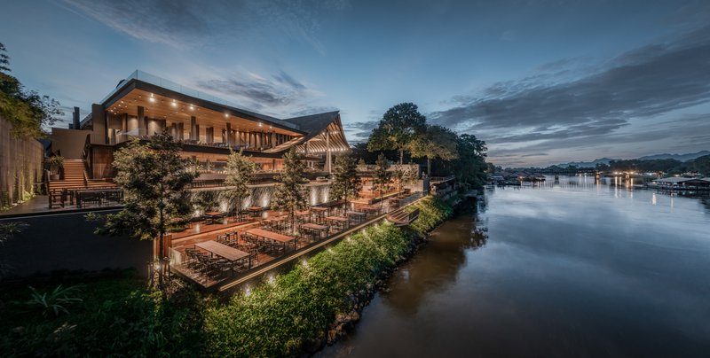 Riverside view of the illuminated complex with tiered roofs and terraced seating at dusk