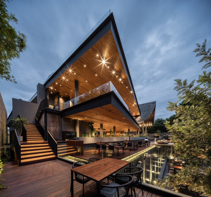 Exterior view of the angular timber roof canopy above tiered decks at twilight