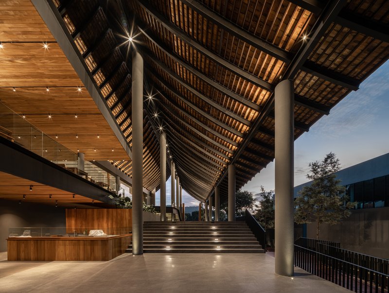 Covered entrance staircase with exposed timber rafters and cylindrical columns at dusk