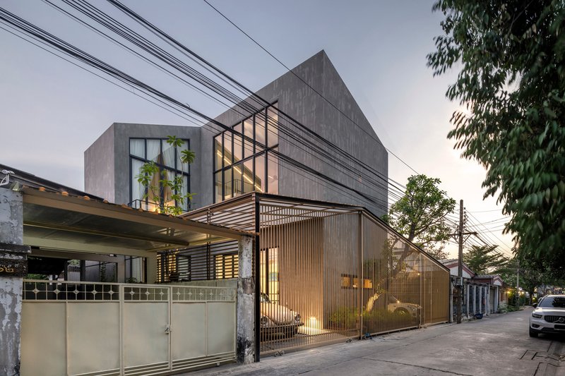 Dusk view of the residence with glowing translucent screen, cantilevered terrace, and overhead utility wires