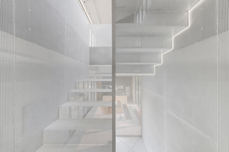 View through translucent perforated metal stair enclosure revealing the dining area beyond