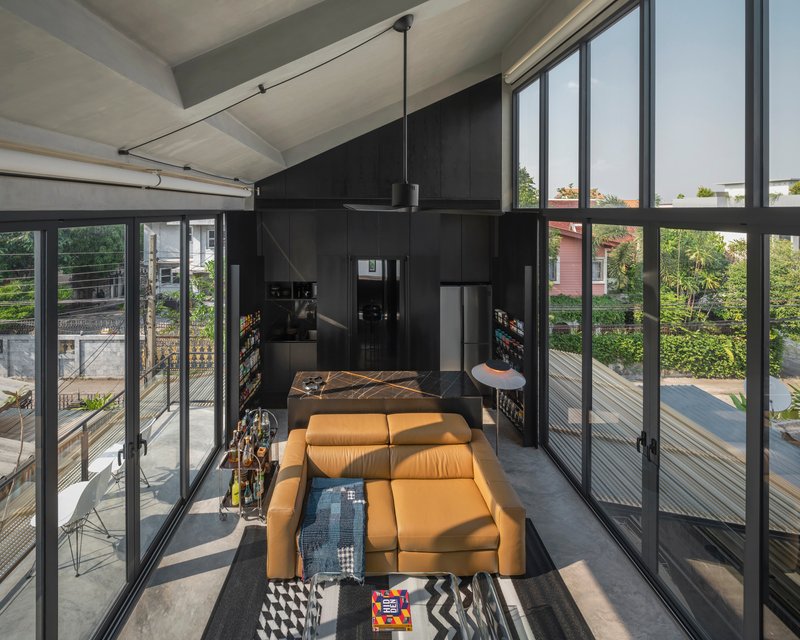 Open living room framed by black steel doors leading to timber decks with afternoon sunlight streaming through