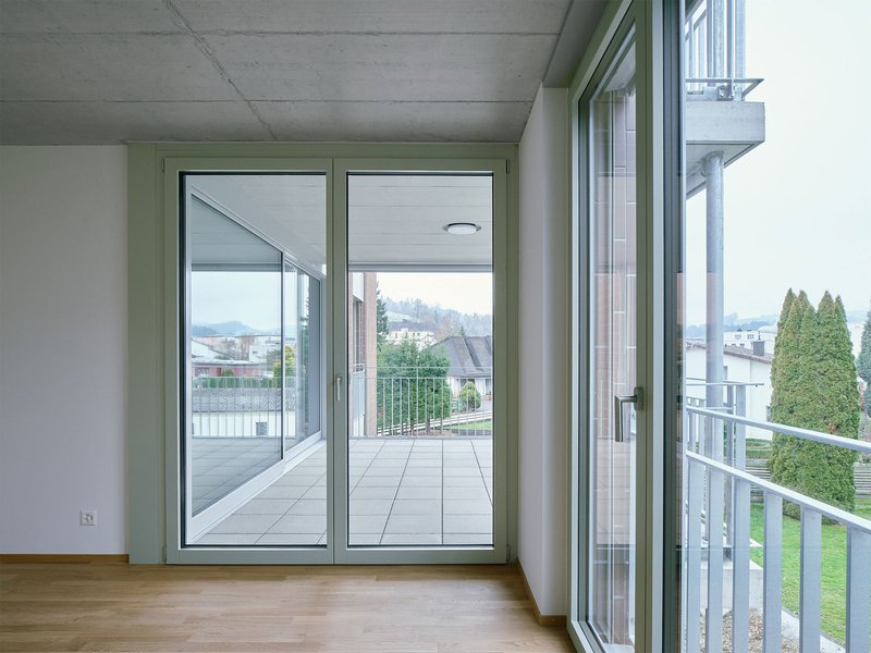 Corner room with sliding glass doors opening onto a shared terrace with metal railings