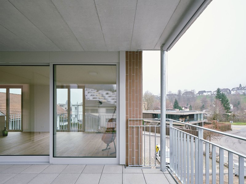 Covered balcony with vertical timber screen and metal railing overlooking a residential street in winter