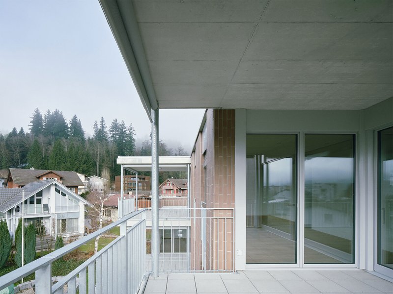 Recessed balcony with concrete soffit and timber cladding column facing a forested hillside