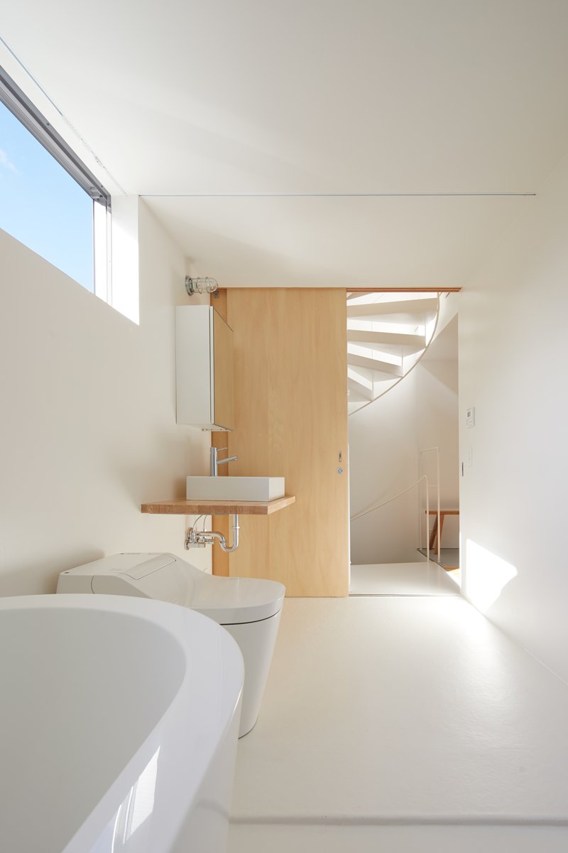 Bathroom with timber partition and floating sink looking toward the spiral staircase beyond