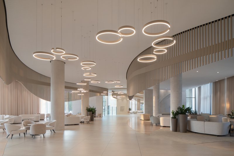 Lobby interior with circular ring pendant lights suspended from a curved soffit above cylindrical columns