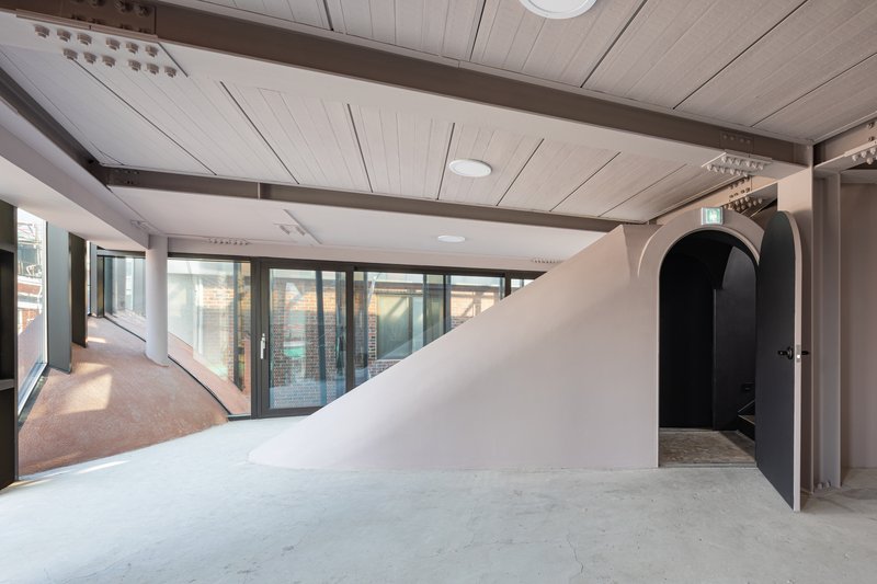 Interior corridor with white curved wall, arched doorway and wood panel ceiling