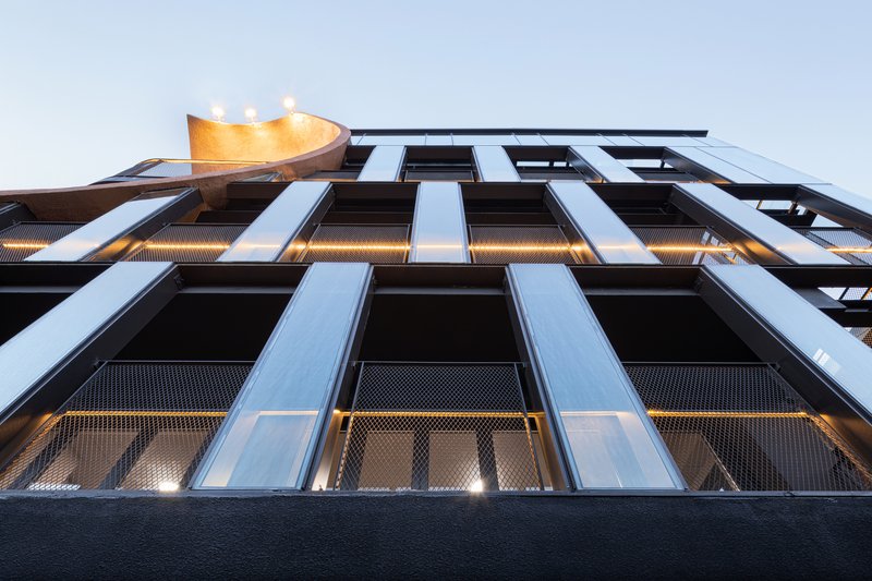 Upward view of the black metal and perforated mesh facade at twilight