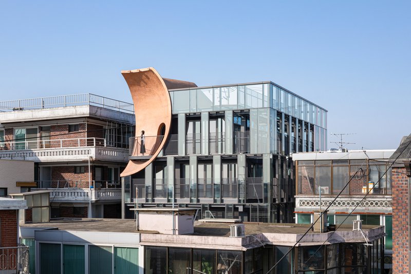 Rooftop view showing the curving copper-toned element rising above the glazed rear elevation