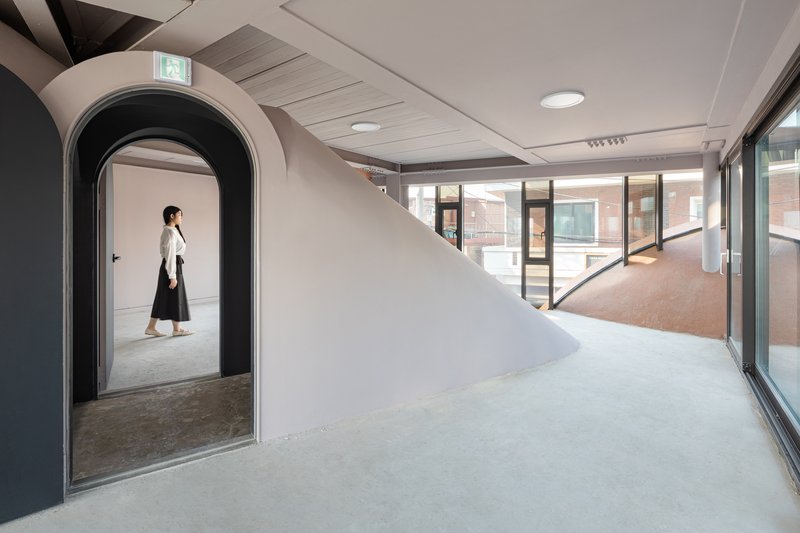 Interior with arched doorway framing a figure and glazed corridor beyond