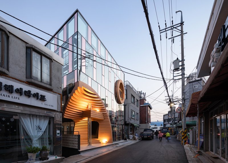 Streetscape view showing the facade between neighboring buildings beneath overhead power lines at dusk