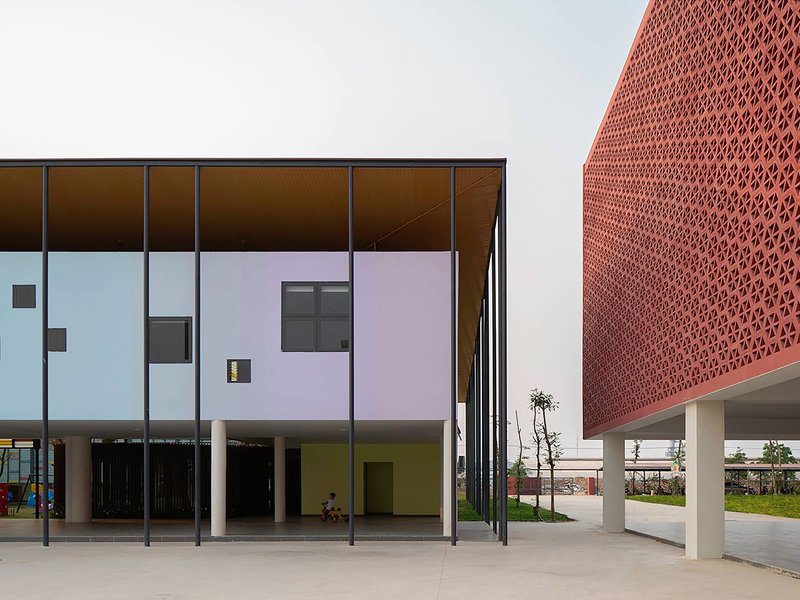 Corner view of the glazed colonnade with pastel panels and perforated terracotta screen volume beyond