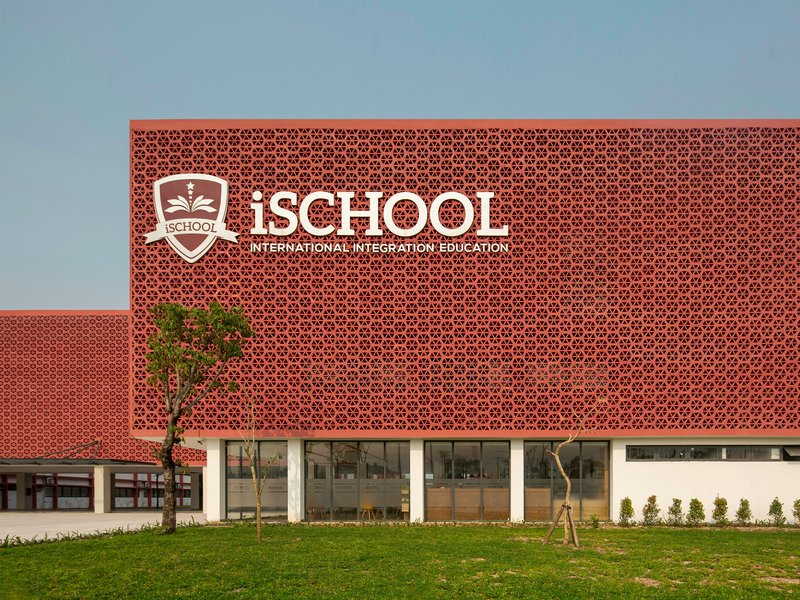 Perforated terracotta screen wall above glazed ground floor with young trees planted in front
