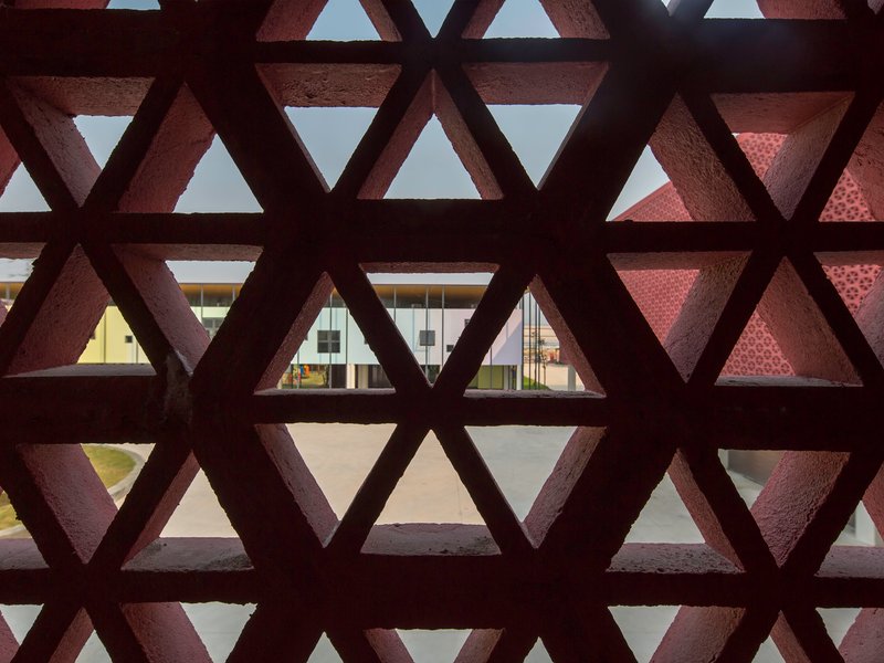 View through triangular lattice screen showing courtyard with another patterned facade beyond