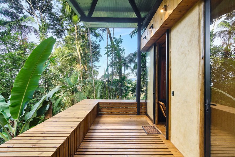 Timber deck terrace with built-in bench and sliding glass doors under exposed steel roof frame