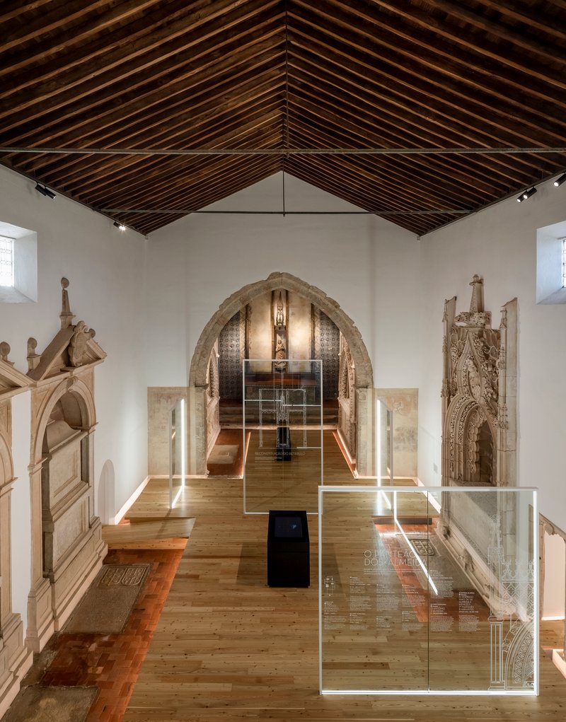 Gallery hall with exposed timber rafters and glass display cases on oak flooring